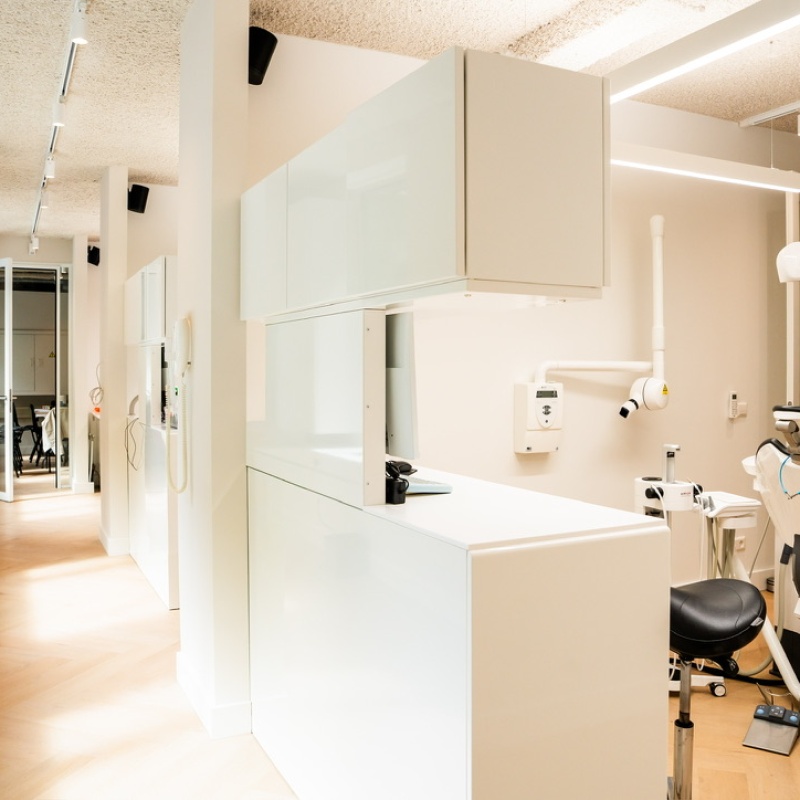 Treatment room with a white cabinet wall, dental chair and X-ray unit