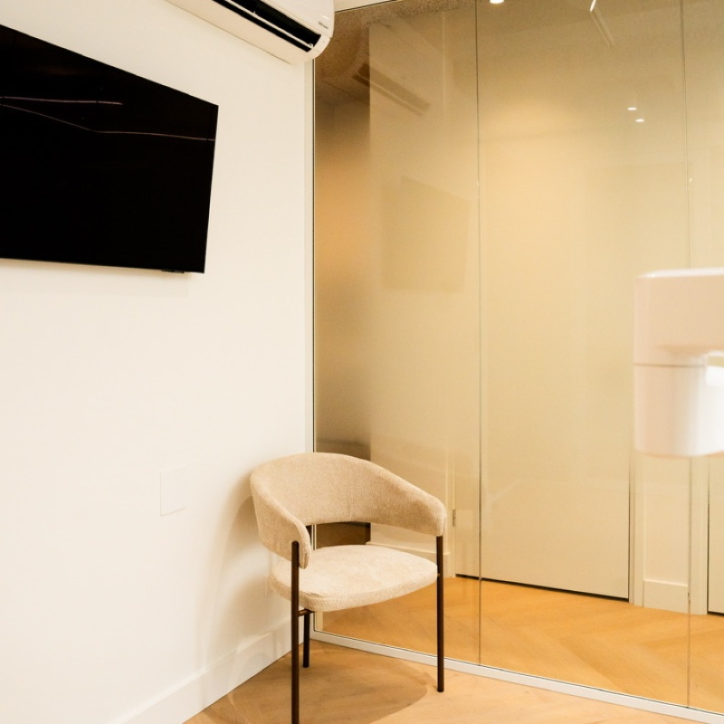 Treatment space with a waiting chair, TV and mirrored wall