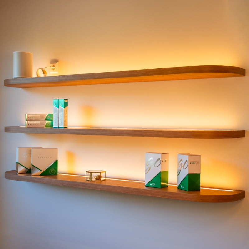 Illuminated wooden wall shelves with care products in the dental practice